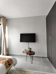 Un dormitorio con una cama y una mesa con un televisor en la pared. en Solara Loft, en Nairobi