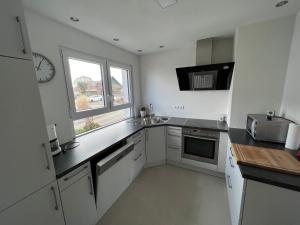 Una cocina blanca con fregadero y microondas. en Ferienwohnung Arnold, en Leutkirch im Allgäu