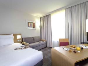 una habitación de hotel con una cama y un sofá en Novotel Perpignan Nord Rivesaltes, en Rivesaltes