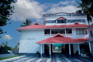 a large white building with a red roof at Ocean Queen Palace Kovalam in Trivandrum +5 photos