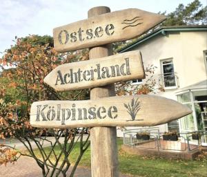 a wooden street sign in front of a house at Apartmenthaus-Usedom Kajüte 10 in Kolpinsee +8 photos