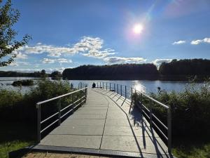 a walkway over a lake with a person on it at Apartmenthaus-Usedom Kajüte 10 in Kolpinsee