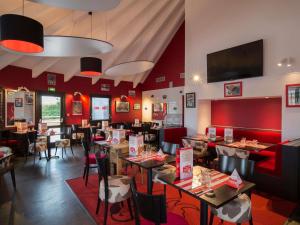 un restaurant avec des murs rouges, des tables et des chaises dans l'établissement Hotel ibis Narbonne, à Narbonne