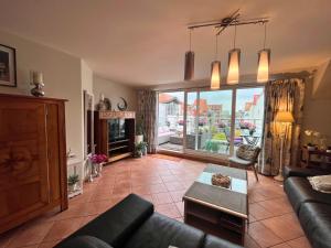 ein Wohnzimmer mit Couch und großem Fenster in der Unterkunft Le Charming duplex lumineux avec balcon, terrasse ensoleillée & parking in Knokke-Heist