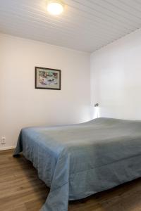 un letto in una stanza bianca con un quadro sul muro di Jukuheikki a Kalajoki