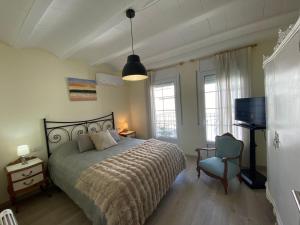 a bedroom with a bed and a chair and a television at Los tres castells in La Senia