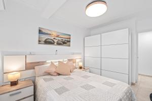 a white bedroom with a bed and a large window at Geani in La Marina