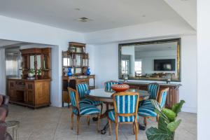 een eetkamer met een tafel, stoelen en een spiegel bij Atlantic Sky Penthouses - Breathtaking Views in Kaapstad
