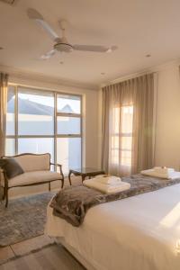 een slaapkamer met een bed, een stoel en een raam bij Atlantic Sky Penthouses - Breathtaking Views in Kaapstad