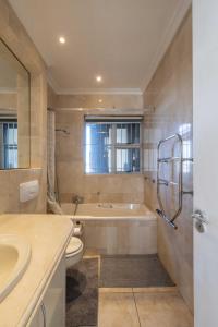 een badkamer met een bad, een toilet en een wastafel bij Atlantic Sky Penthouses - Breathtaking Views in Kaapstad +121 foto's