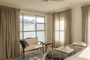 een slaapkamer met een bed, een stoel en een raam bij Atlantic Sky Penthouses - Breathtaking Views in Kaapstad