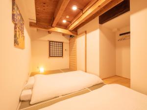 ひとあかり 東山 Hitoakari Higashiyama-A Warm and Modern Machiya Stay في Shimmachidōri: غرفة بها سريرين ونافذة