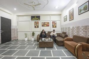 two people sitting on a couch in a waiting room at FabHotel ASP Royal Residency Inn- Janakpuri in New Delhi