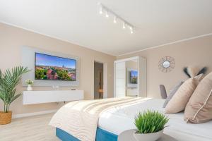 a white bedroom with a large bed and a tv at Amber Premium Apartments in Bydgoszcz