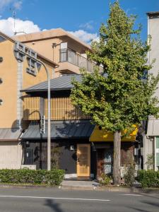 ひとあかり 東山 Hitoakari Higashiyama-A Warm and Modern Machiya Stay في Shimmachidōri: مبنى على جانب شارع فيه شجرة