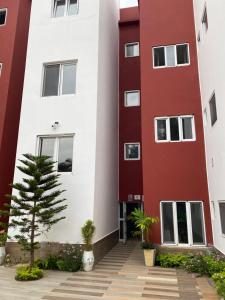a red and white building with a tree in the courtyard at Comfort Corner in Amdalai