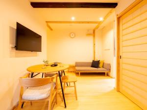 ひとあかり 東山 Hitoakari Higashiyama-A Warm and Modern Machiya Stay في Shimmachidōri: غرفة بها طاولة وكراسي وأريكة