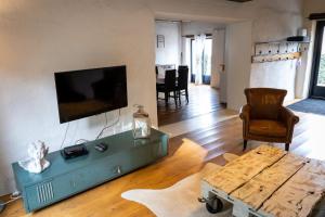 een woonkamer met een tafel en een tv aan de muur bij Maison 5 in Souvigny
