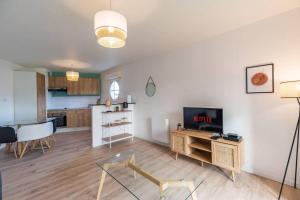 a living room with a television and a kitchen at Appartement neuf proche Guingamp in Ploumagoar +19 photos