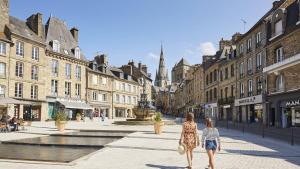two women walking down a city street with buildings at Appartement neuf proche Guingamp in Ploumagoar