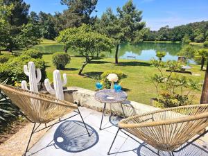 a patio with a table and chairs and a lake at ZEcamping 3 étoiles vue lac environnement calme in Douville