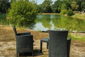 two chairs and a table in front of a lake at ZEcamping 3 étoiles vue lac environnement calme in Douville