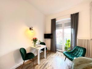 a living room with a table and green chairs at Kapitaenshaus-Lassen-Zimmer-Sindbad in Westerland (Sylt)