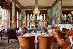 a dining room with a table and chairs and a fireplace at Brownsover Hall Hotel in Rugby