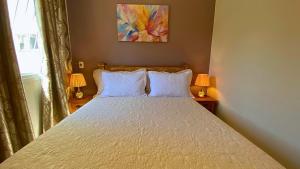 um quarto com uma cama branca com duas lâmpadas em Excelente Apartamento Climatizado em Jacaraipe em Serra