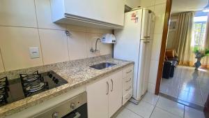 a kitchen with a sink and a stove and a refrigerator at Excelente Apartamento Climatizado em Jacaraipe in Serra