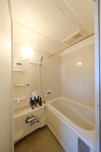 une salle de bain blanche avec une baignoire et un lavabo dans l'établissement Casa Hiro, à Osaka
