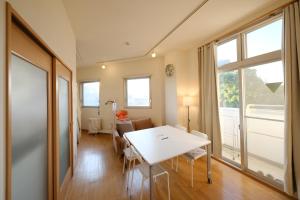 Cette chambre comprend une table blanche, des chaises et des fenêtres. dans l'établissement Casa Hiro, à Osaka 18 autres photos