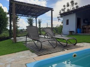 deux chaises assises à côté d'une piscine dans l'établissement Rancho São Miguel Arcanjo, à Caçapava