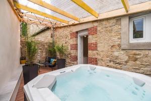a hot tub in a patio with a brick wall at Charmant Duplex avec jacuzzi Guingamp centre in Guingamp