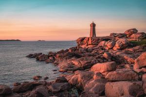 a lighthouse on the rocks near the water at Charmant Duplex avec jacuzzi Guingamp centre in Guingamp
