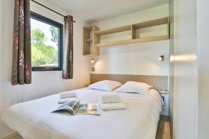 a bedroom with a white bed with two books on it at Camping Les Fontaines in Ivry-la-Bataille +27 photos