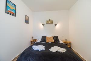 a bedroom with a large bed with two towels on it at Le T2 Zen de Guingamp confort au coeur de la ville in Guingamp +11 photos