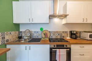 a kitchen with white cabinets and a sink at Le T2 Zen de Guingamp confort au coeur de la ville in Guingamp