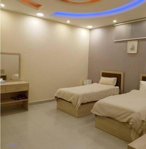 Una habitación de hotel con dos camas y un techo azul. en saqf alraha For serviced apartments, en AÅŸ Åžaá¸©anah
