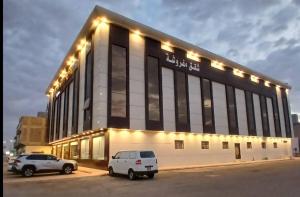 Un edificio grande con dos coches estacionados en un estacionamiento. en saqf alraha For serviced apartments, en AÅŸ Åžaá¸©anah