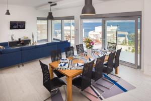 una sala da pranzo con tavolo, sedie e divano blu di Villa Costabella with heated pool a Posedarje (Possedaria)