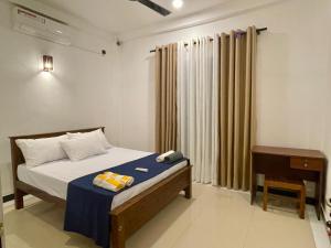 ein Schlafzimmer mit einem Bett und einem Tisch und einem Fenster in der Unterkunft Delight Villa - Ahangama in Ahangama