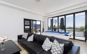 een woonkamer met een zwarte bank en een pooltafel bij CAPE20 Villa in Kaapstad +23 foto's