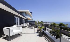 een balkon met witte stoelen en planten in een gebouw bij CAPE20 Villa in Kaapstad