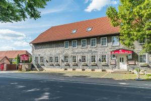 um edifício antigo com um telhado vermelho numa rua em Bei Meier`s zum weißen Roß em Königslutter am Elm