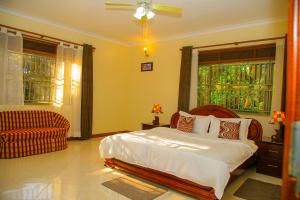 a bedroom with a bed and a couch and a window at Calm Suites Kampala in Kampala