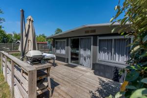 Oosterendglamping luxe caravan的木甲板上设有烧烤架和房屋
