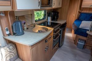 Oosterendglamping luxe caravan的厨房配有水槽和炉灶。