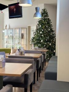 a christmas tree in a restaurant with tables and chairs at Green Vilnius Hotel in Vilnius