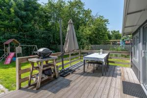Oosterendglamping luxe caravan的一个带烧烤架、桌子和遮阳伞的甲板 更多7张照片